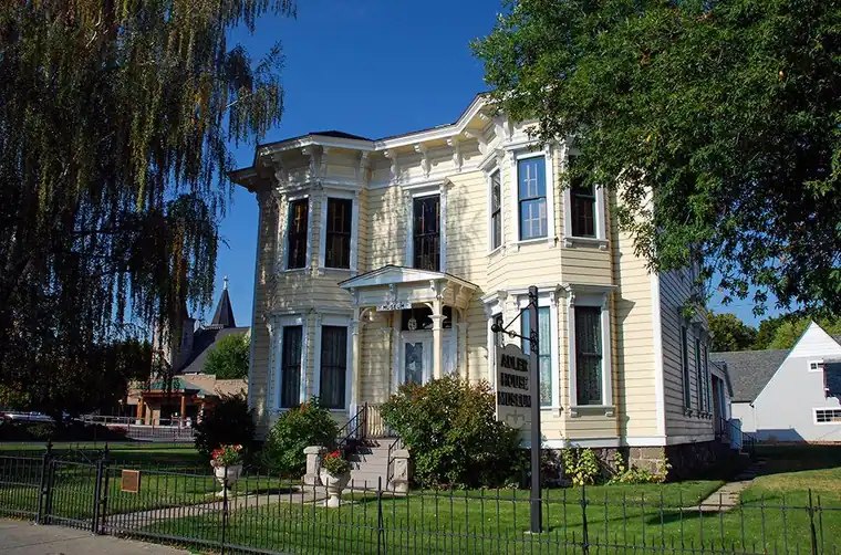 Italianate house behind an iron fence with a new shingle roof