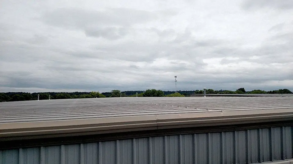 Low-slope metal deck edge under an overcast sky