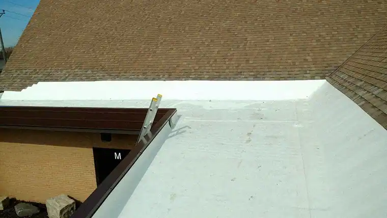 White single-ply flat roof section meeting a shingled slope