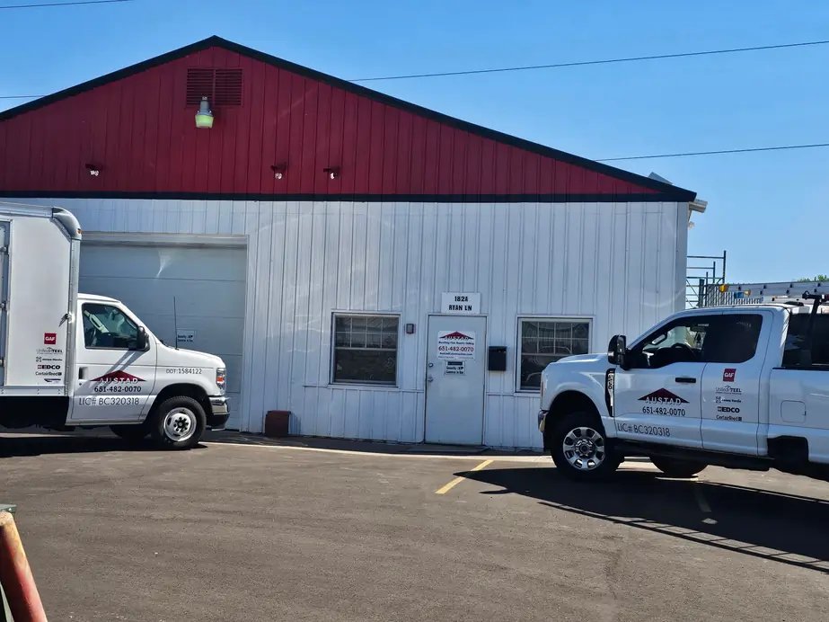Austad Construction's white shop with a red gable on Ryan Lane, two lettered company trucks parked out front